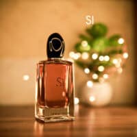 A 100ml bottle of Giorgio Armani Si Eau de Parfum with a black cap on a brown table.