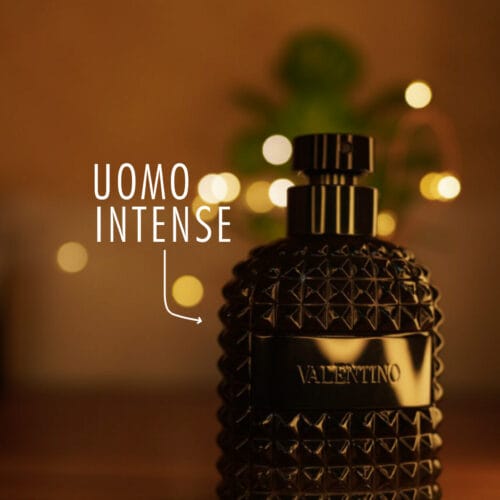 A 100ml bottle of Valentino Uomo Intense Eau de Parfum with a black cap on a brown table.