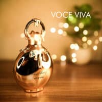 A 100ml bottle of Miss Armaf Voce Viva Eau De Parfum with a gold bottle and cap on a brown table.
