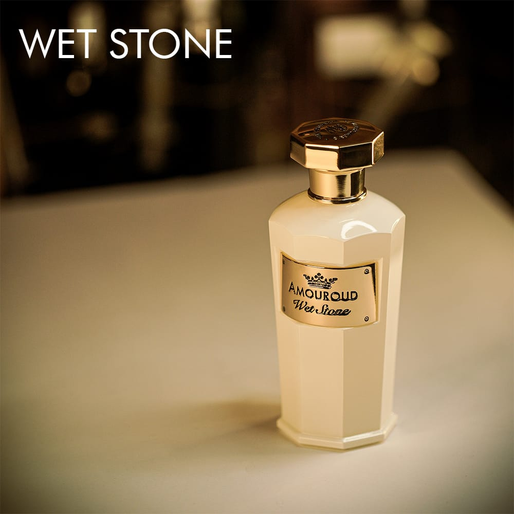 A 100ml bottle of Amouroud Wet Stone Eau de Parfum white bottle golden label on a white table