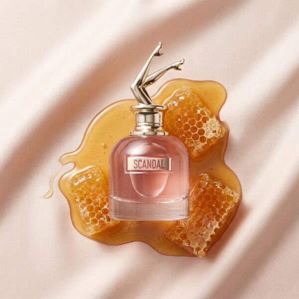 Generated Image December 04, 2025 - 9_16AM Vegan perfume bottle labeled "SCANDAL" with honeycomb and honey on satin fabric.