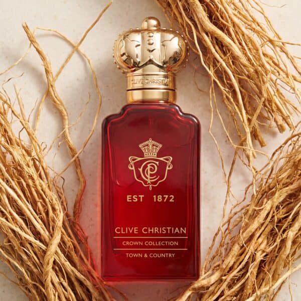 39 Luxurious Clive Christian Crown Collection perfume in a deep red bottle with gold crown cap, resting on dried botanical twigs.