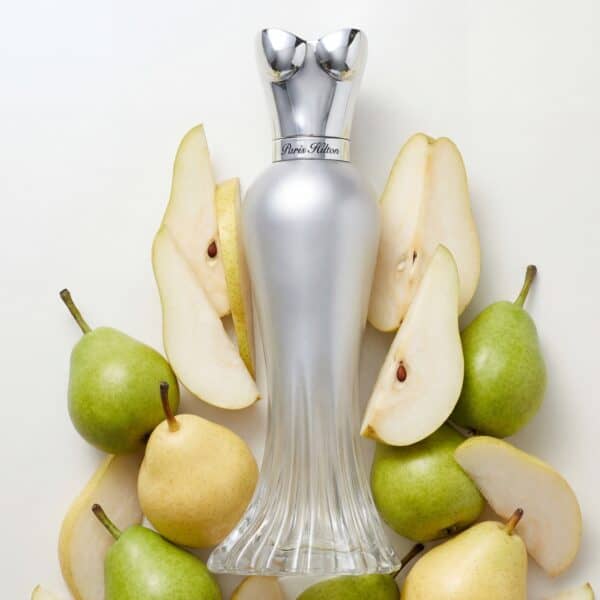 46 Fresh green and yellow pears with sliced pieces surrounding a luxurious perfume bottle.