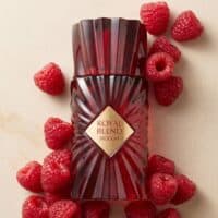 Vivid raspberry-scented perfume bottle surrounded by fresh raspberries, showcasing luxury fragrance and fruity notes.